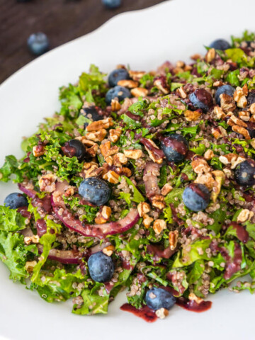 Quinoa Salad with kale, a super-food salad dressed for a party. Topped with crunchy pecans and tangy blueberry dressing. You'll love this make-ahead lunch.
